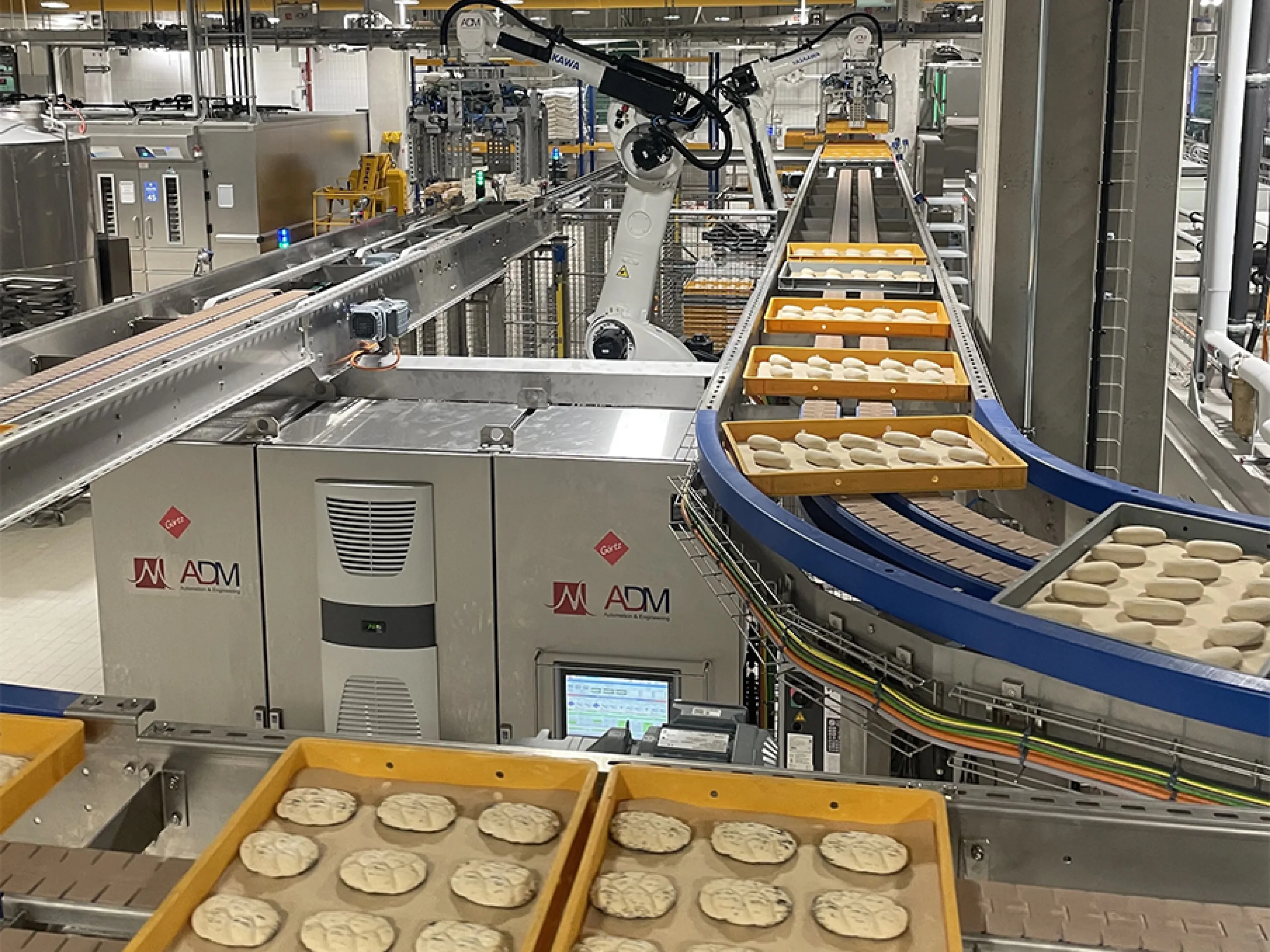 Zwei der vier „Motoman GP180“-Roboter entnehmen die Dielen am Frosterauslauf und setzen sie auf ein Förderband um.