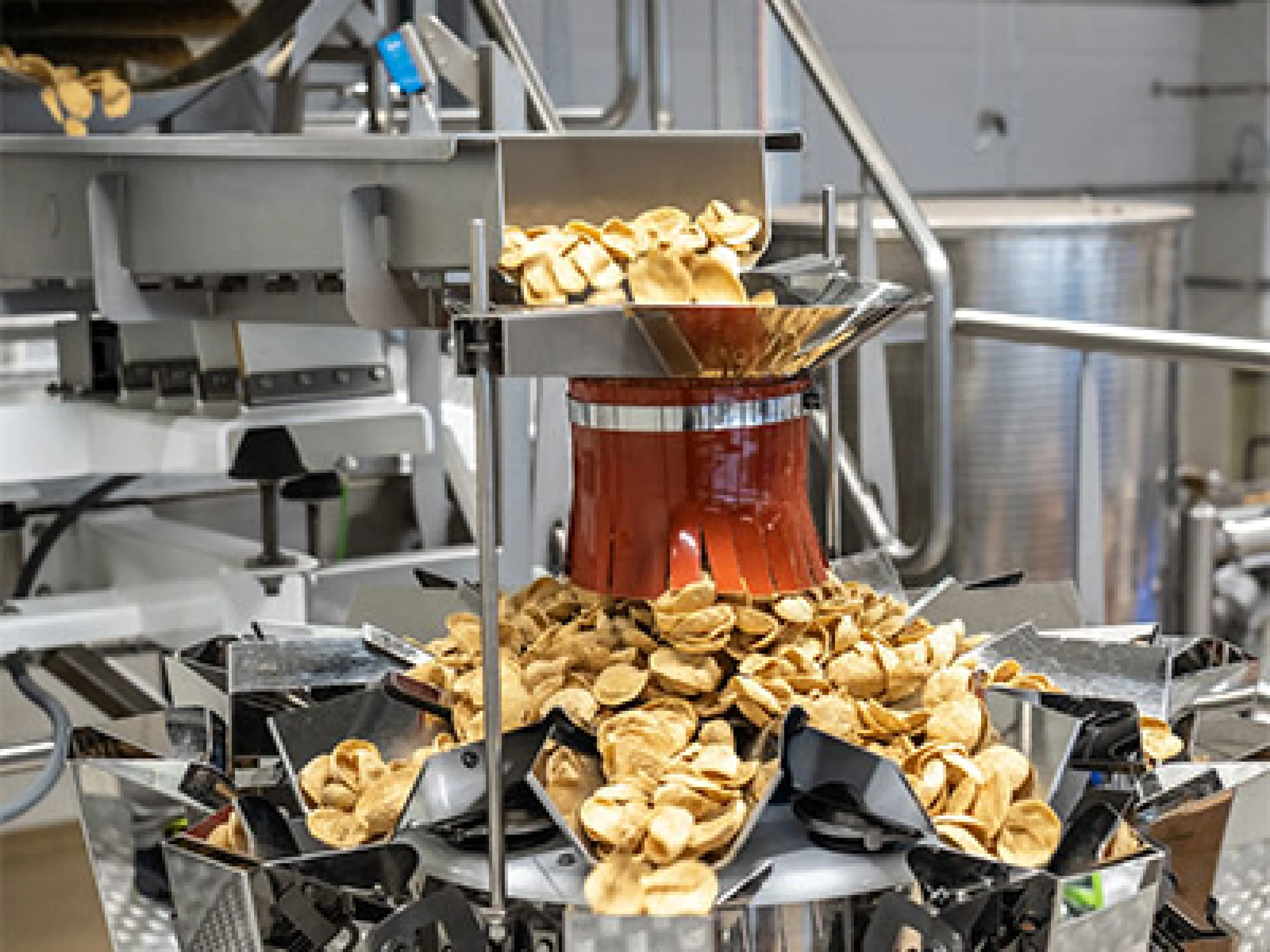 Über den Verteilteller und automatisch gesteuerte Vibrationsrinnen erreichen die Snacks die Schalen der Mehrkopfwaage