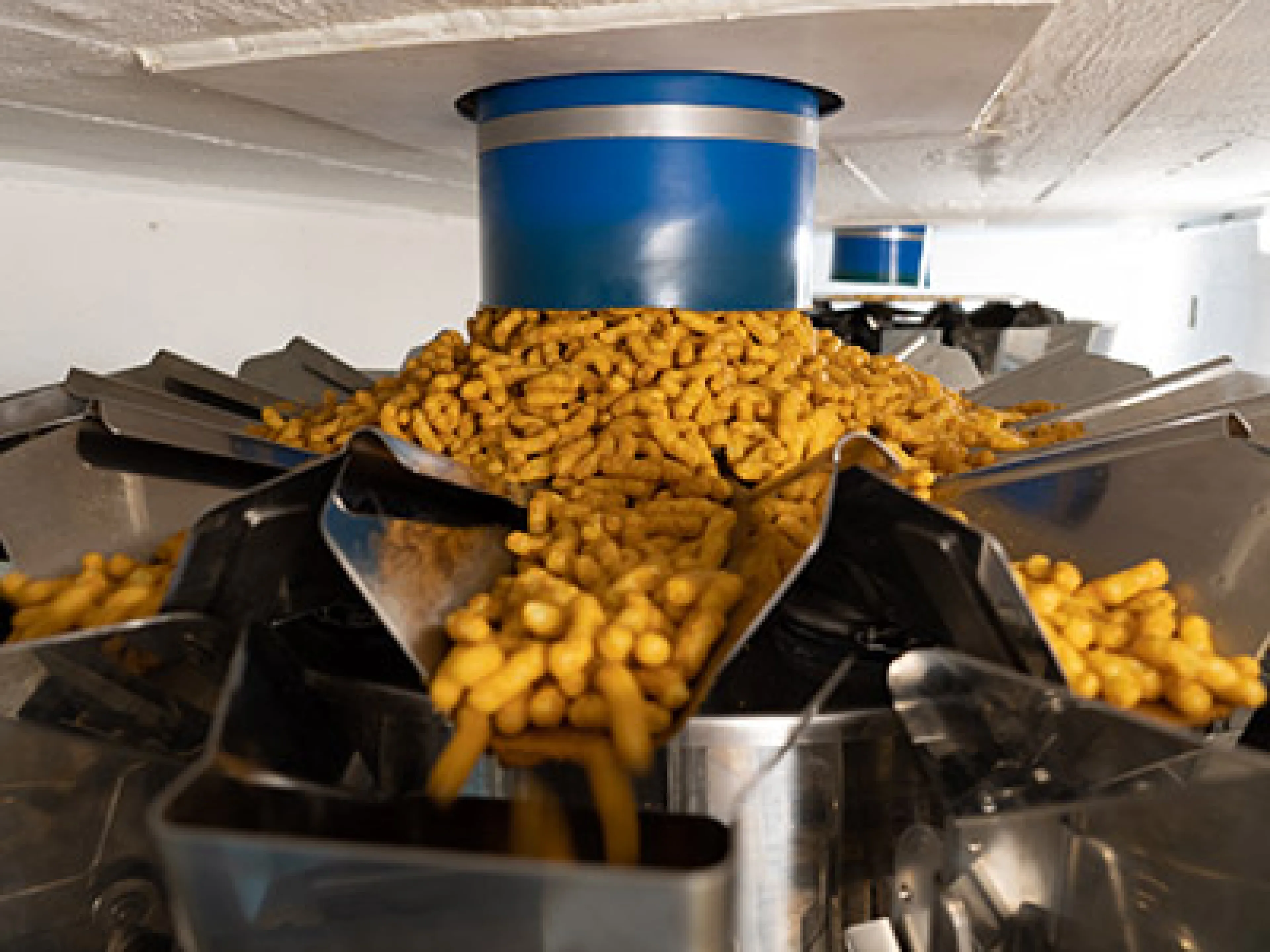 Vibrierende Rinnen fördern die Snacks vom Verteilteller der Mehrkopfwaage zu den Schalen