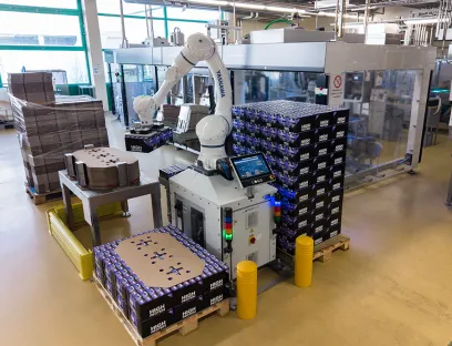 In der Privatmolkerei Bauer entnimmt der Cobot die Trays aus dem vorgeschalteten Packer, setzt sie auf Paletten um und fügt selbstständig Karton-Zwischenlagen ein