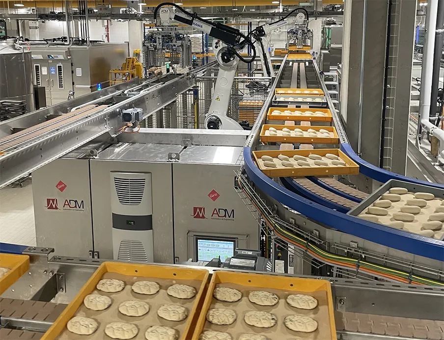 Zwei der vier „Motoman GP180“-Roboter entnehmen die Dielen am Frosterauslauf und setzen sie auf ein Förderband um.